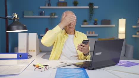 Home-office-worker-old-man-gets-frustrated-while-looking-at-phone.